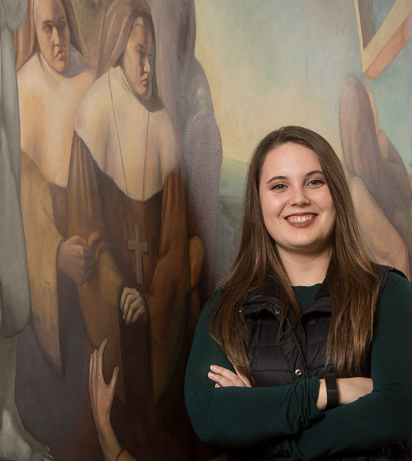 Kaylee Cunningham next to a campus mural