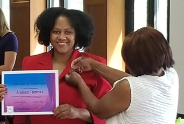 Student Andrea Thomas receives a pin from her family member in recognition of her success as a first-generation student.