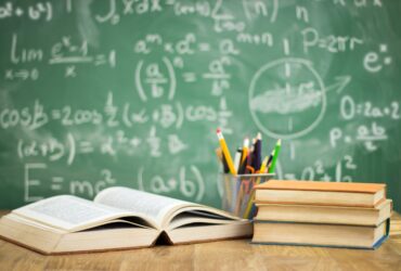 Chalkboard with books and cup of pencils in classroom